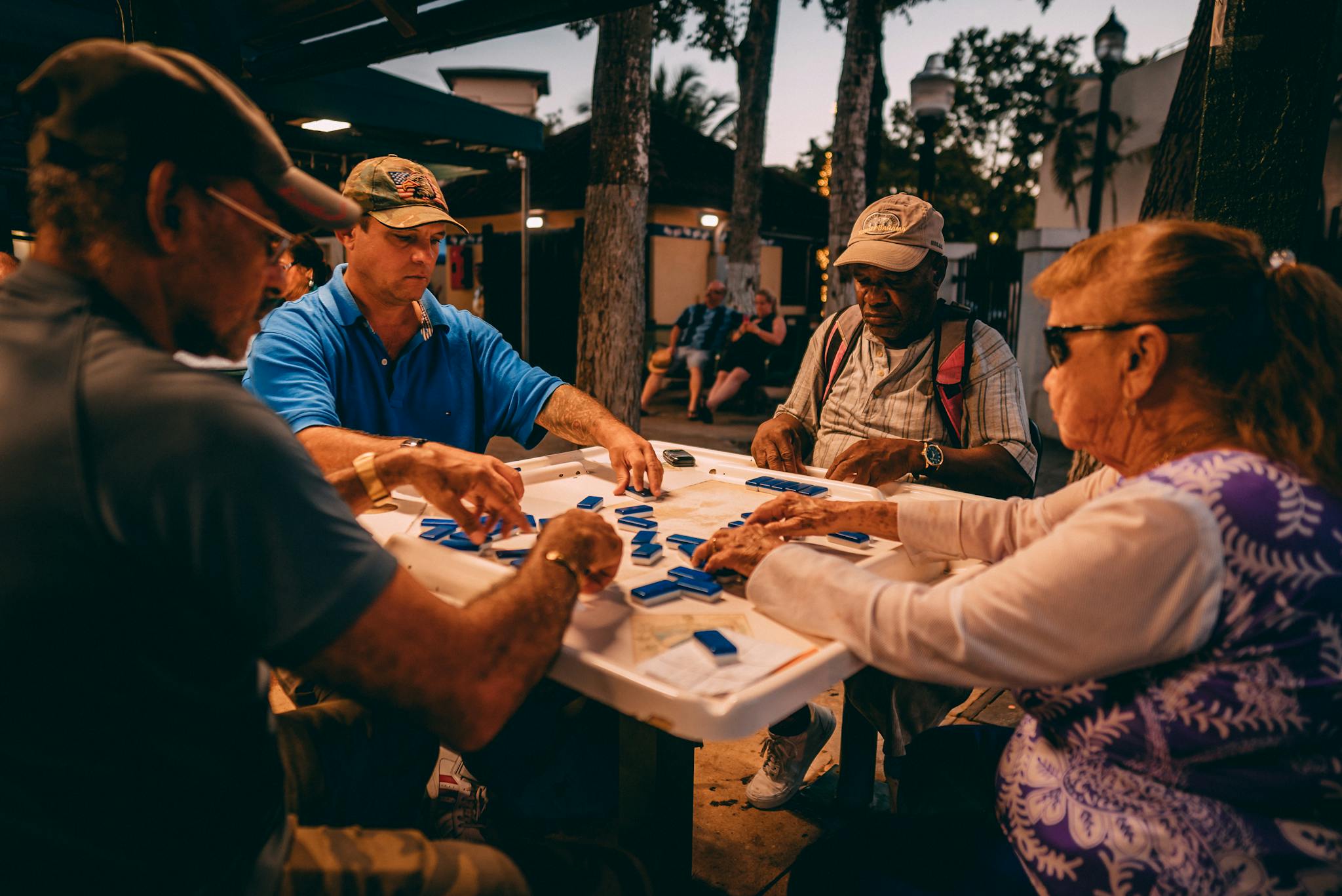 A group of people engaging in a game of mahjong outdoors in Miami, FL.